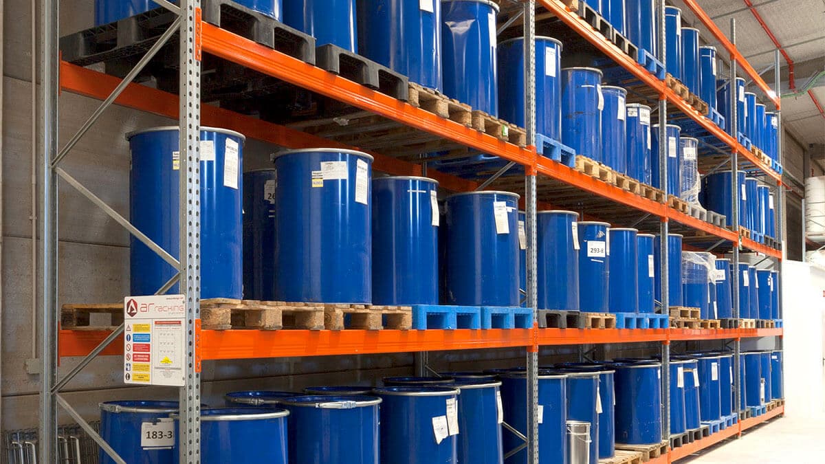 Racked pallets of blue chemical drums in a warehouse